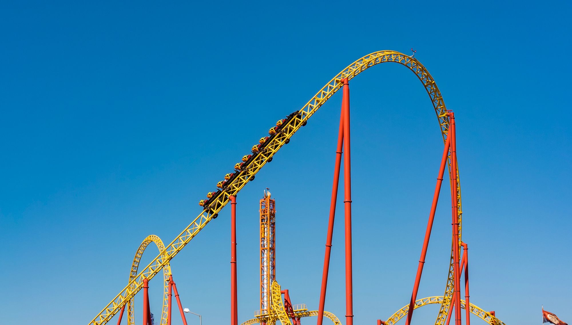 Une vue saisissante d'une montagne russe dans un parc d'attractions, avec en toile de fond un ciel bleu limpide.